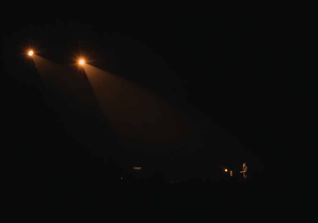 Speaker on a dimly lit stage with warm spotlights